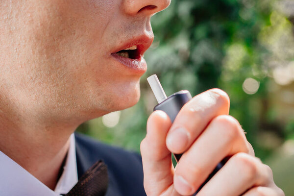 the man smokes. close-up. electronic cigarettes. tobacco heating system.