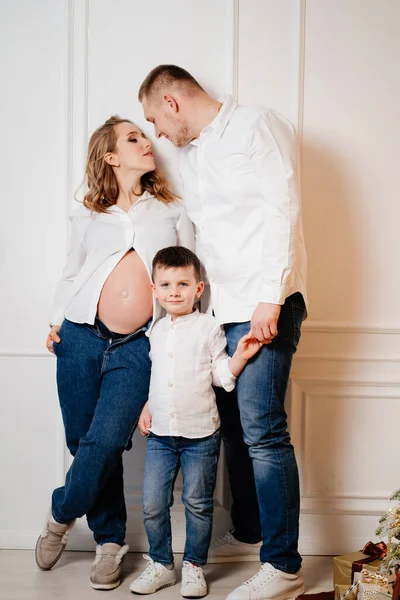 Famille heureuse. mère enceinte avec son fils et son père en jeans et une chemise blanche — Photo