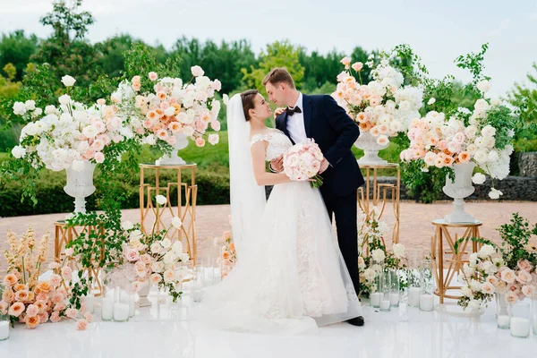 Braut und Bräutigam im Bereich der Hochzeitszeremonie aus lebenden weißen und rosa Blumen. — Stockfoto