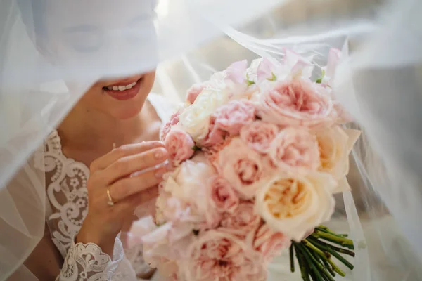 Eine schöne junge Frau in einem Spitzengewand mit einem Blumenstrauß. Brautschleier — Stockfoto