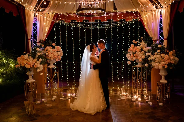 Jeunes mariés lors de la cérémonie de mariage en soirée dans le parc parmi les ampoules et les guirlandes. — Photo