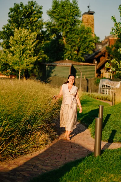 Una mujer camina por un sendero en el jardín de un club de campo o parque al atardecer. — Foto de Stock