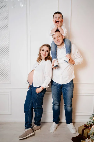행복 한 가족. 청바지와 흰색 셔츠를 입은 채 아들 과 아버지와 함께 있는 임신부 — 스톡 사진