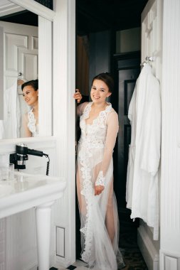 Banyonun kapısında dantel bornozlu güzel bir kadın.