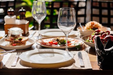 Açık terasta salata ve atıştırmalıklarla servis edilen ahşap masa.