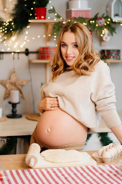 Yeni yıl mutfağında çıplak karnına sahip hamile bir kadın. hazırlık hamuru — Stok fotoğraf