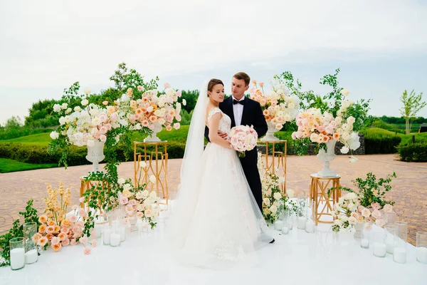 Nevěsta a ženich v oblasti svatební obřad živých bílých a růžových květin. — Stock fotografie