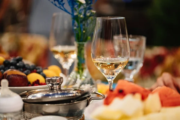 Um copo de vinho branco e um buquê de flores azuis na mesa servida. — Fotografia de Stock