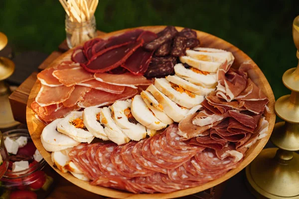 Assorted meat cuts. sausage, meatloaf, ham on a round wooden plate. — Stock Photo, Image