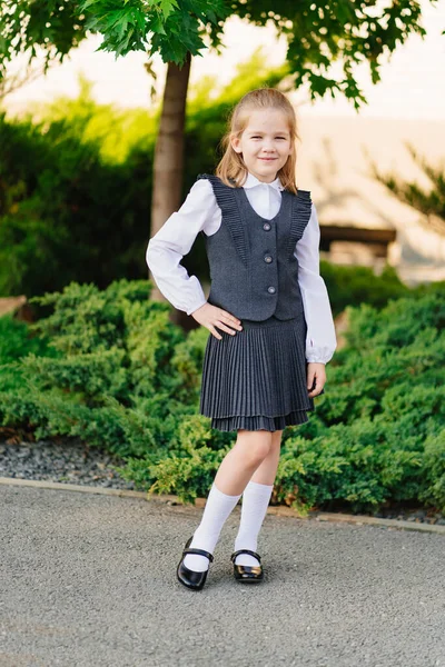 Uma menina bonita em um uniforme escolar cinza. venda de roupas para escolares. — Fotografia de Stock