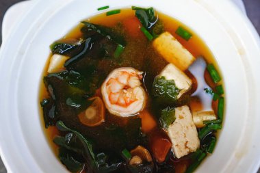 Karidesli çorba, yosun, mantar ve beyaz tabakta tofu peyniri. en üstteki görünüm.