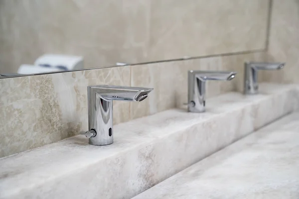 Rubinetti lavabo a infrarossi senza contatto. impianto idraulico per bagni e servizi igienici pubblici. — Foto Stock