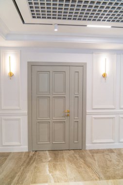 Beyaz iç kısımda büyük, gri ahşap bir kapı. Klasik 