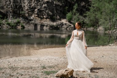 Dağ Gölü kıyısındaki fotoğraf çekiminde beyaz gelinlikli çekici bir kadın.