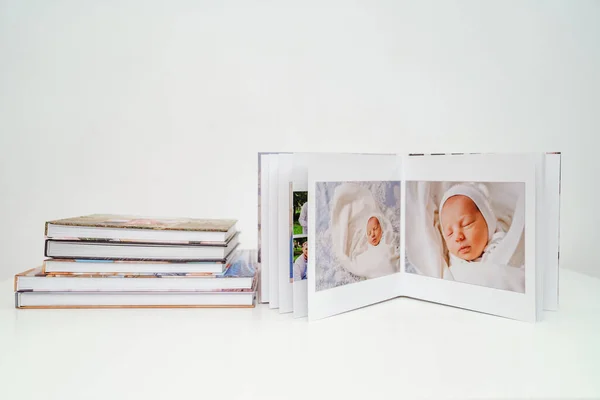 on white background photobooks. open photo album from photo shoot with a newborn