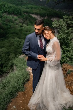 Dağlarda bir düğün töreninde yeni evlilere sarılan güzel bir çift.