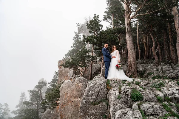 Un jeune marié sur un rocher dans une forêt de montagne. lune de miel. — Photo