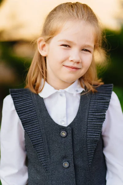 En söt tjej i grå skoluniform. Försäljning av kläder för skolbarn. — Stockfoto