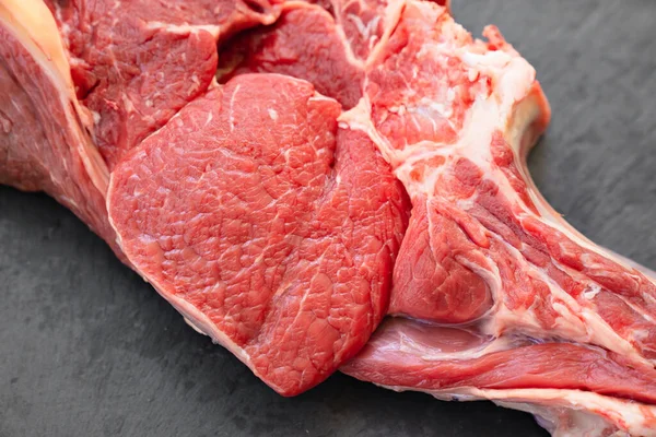 Trozo de carne de res en hueso sobre fondo negro.productos agrícolas naturales y ecológicos —  Fotos de Stock