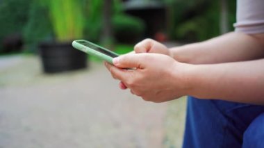 Kadın elinde bir akıllı telefon tutuyor ve yayınları sosyal ağlardan izliyor.