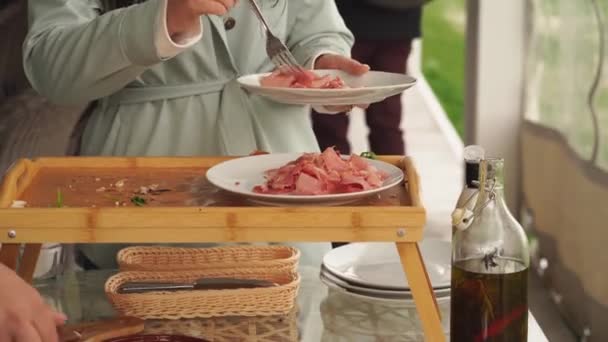 Kobieta wkłada kawałki suszonego mięsa do talerza — Wideo stockowe