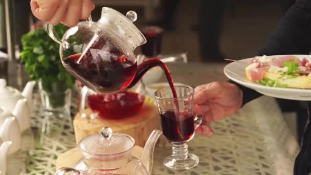 Mężczyzna wlewa gorącą herbatę do szklanki. napój grzewczy — Wideo stockowe
