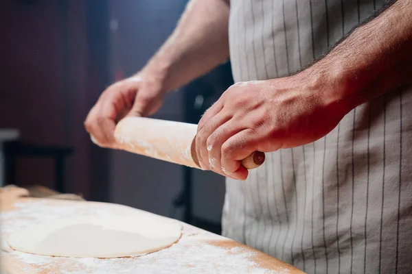 Hände rollen den Teig zu einer dünnen Schicht. Pizza, Nudeln oder Pitta zu Hause kochen — Stockfoto