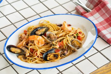 Ekoseli masa örtüsüyle oval tabakta deniz mahsullü spagetti.. 