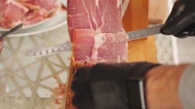 Eldivenli bir adam ziyafet için ince kuru et parçaları keser.. 