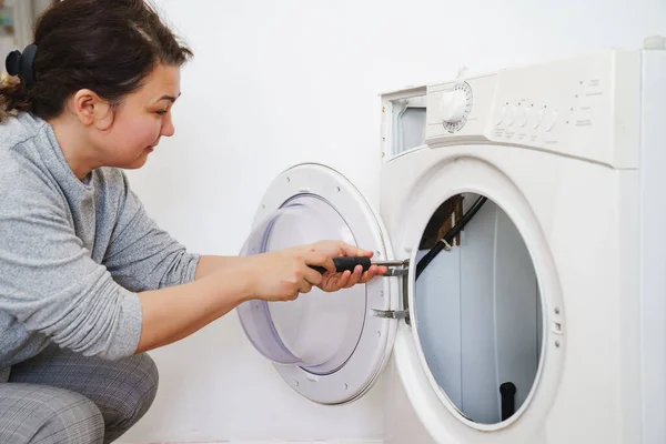 La mujer repara la lavadora, se desmonta en partes — Foto de Stock