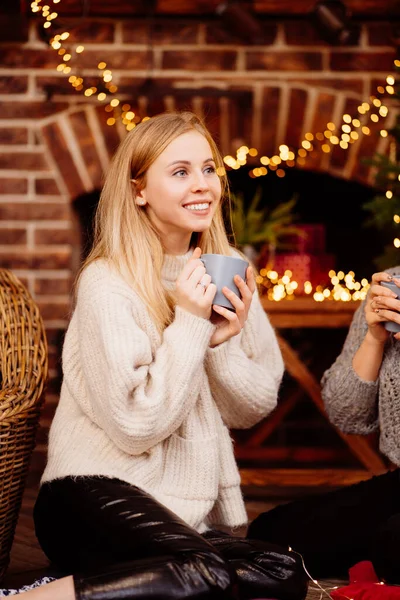 En vacker blond dricka kakao vid nyår öppen spis — Stockfoto