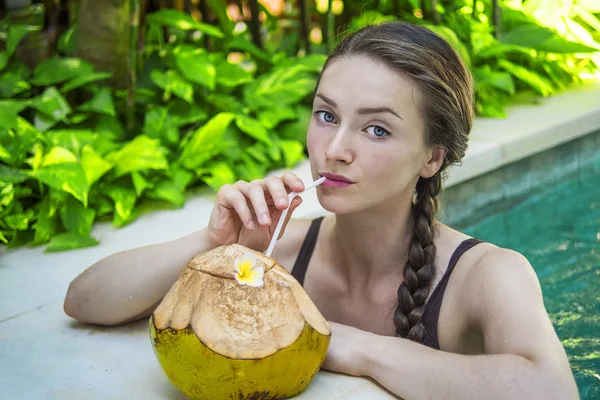 Schöne junge Frau trinkt Kokoswasser Stockfoto