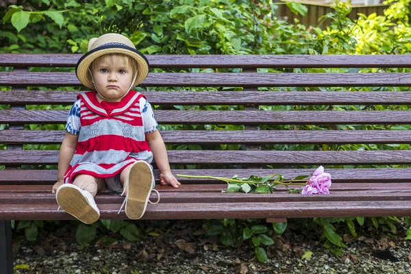 Грустный малыш сидит на скамейке — стоковое фото