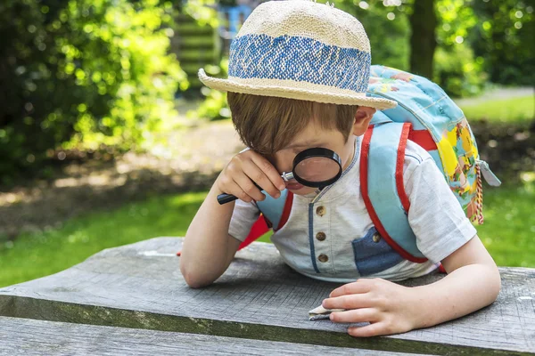 Söt pojke leker med ett förstoringsglas — Stockfoto