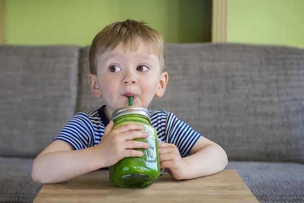 Niño bebiendo un batido verde Imagen de archivo