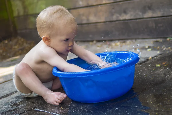 Baby spielt mit einer Wanne Wasser — Stockfoto