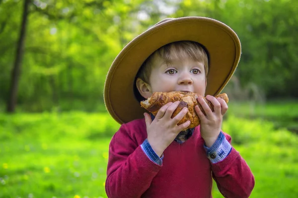 Lindo chico comiendo un croissant — Foto de Stock