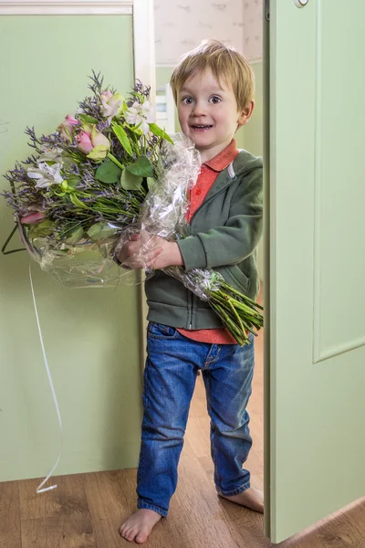 Chico divertido trayendo flores — Foto de Stock