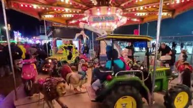 BUDAPEST, HUNGARY NOVEMBER 28, 2025: parlak, renkli bir çocuk atlıkarınca şehir merkezinde bir kış bayramı pazarında dönüyor. Bu geleneksel panayır gösterisinde çocuklar için aydınlatılmış ışıklar ve dekoratif hayvan figürleri yer alıyor.