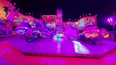 BUDAPEST, HUNGARY 8 ARALIK 2025: Şehir merkezindeki bir gece fuarı sırasında ışıl ışıl aydınlatılmış bir break dans eğlence gezisi düzenlenir. Görüntüler, arka planda renkli neon ışıkları ve kalabalıkla çekimin dönen hareketini gösteriyor..