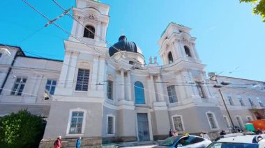 SALZBURG, AUSTRIA ECTOBER 3, 2025: İkiz kuleleri ve merkezi kubbesinin yer aldığı Dreifaltigkeitskirche, Kutsal Üçlü Kilisesi 'nin cephesine geniş açılı bir bakış. Barok mimarisi park halindeki arabalarla sokak seviyesinden yakalanır.