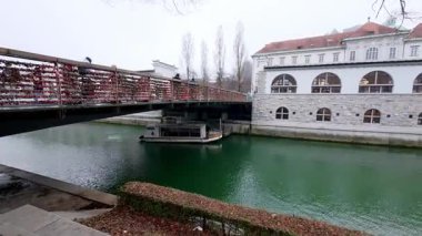 Ljubljanica nehri gün boyunca tarihi Plecnik Kapsamlı Pazar sütunları boyunca akar. Ünlü mimari simgesi, deniz kenarındaki setin üzerinde belirgin bir şekilde duruyor..
