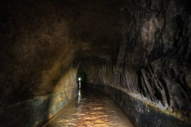 Taş su kanalı kayalar ve taşlarla çevrili ve sonunda bir ışık yolu var.