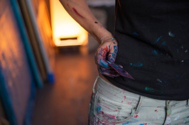 Stüdyoda resim yapmak için kullandığı bir aletle genç bir kadın ressamın elini görebilirsiniz.