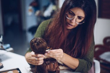 Uzun saçlı genç kadın bez bebek yapıyor.