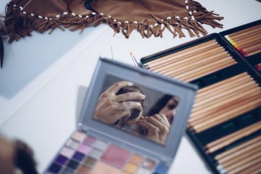 Genç bir kadın bez bebeğinin yüzünü boyuyor.