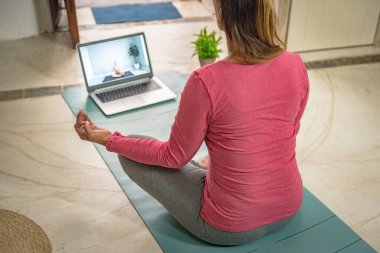 Beyaz bir kadın evde dizüstü bilgisayarıyla ağlama alıştırması yapıyor.