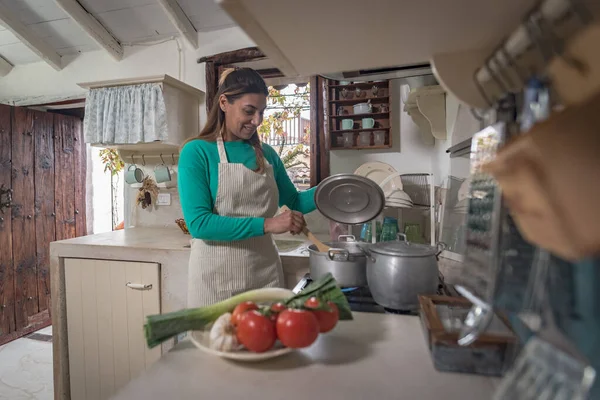 woman in a traditional vintage kitchen making a meal with old pots and vegetables