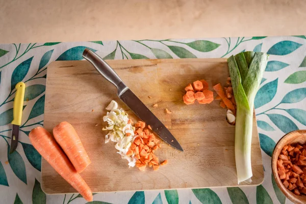 kitchen board with cut carrot and leek vegetables prepared for cooking