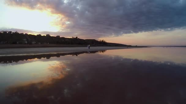 Zon daalt over Stille Oceaan en mensen krijgen rest aan zandstrand op herfst avond. Luchtfoto — Stockvideo